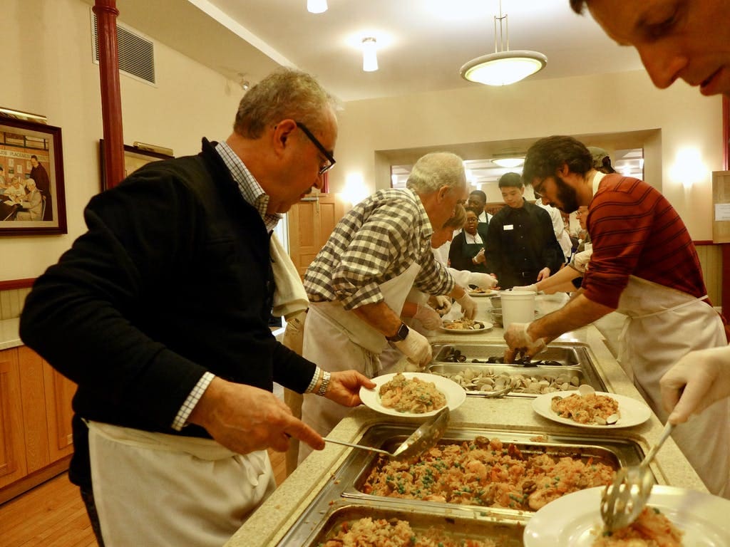 Workers get paella ready for a Ministry of Caring Spanish dinner