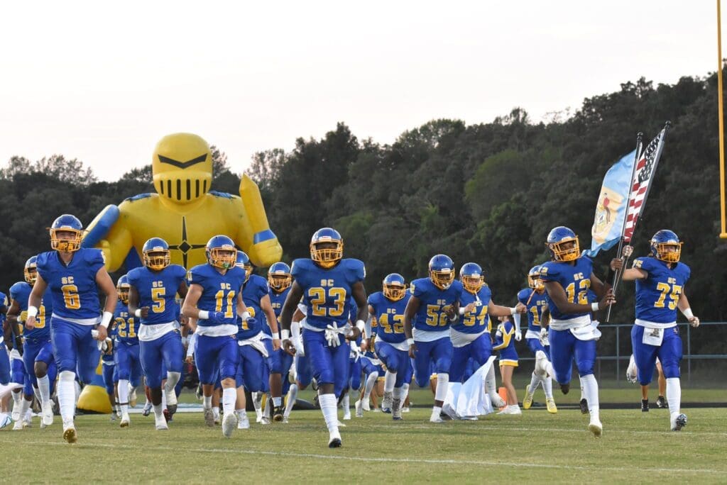Sussex Central football team running on tot he field photo by Ben Fulton