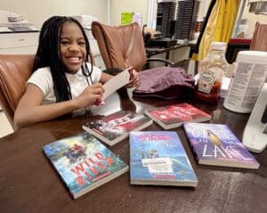 Fourth-grader Alaijah Thompson with her collection of new books. (Jarek Rutz/Delaware LIVE News)