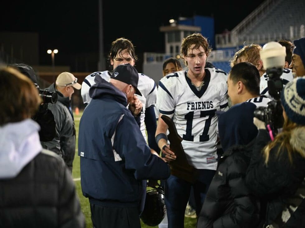Wilmington Friends football player quarterback Robby Tattersall hands the state championship trophy to his grandfather Bob Tattersall photo by Nick Halliday new